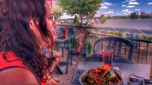 Side view close-up of woman sitting by food on table at restaurant