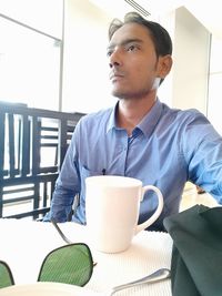 Man looking away while sitting on table