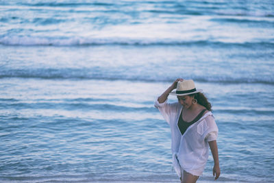 Woman wearing hat standing at beach