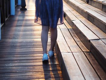 Low section of woman walking on hardwood floor