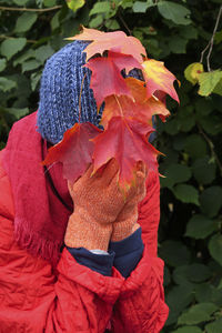 Close-up of woman with red leaves