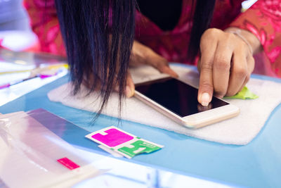 Midsection of woman using smart phone on table