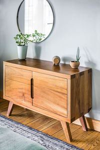 Bed base, bedroom with mat on the floor, clay pot in the background, wooden credenza and mirror.