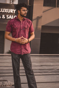 Portrait of young man standing against wall