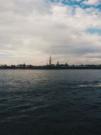 View of lighthouse in sea against cloudy sky