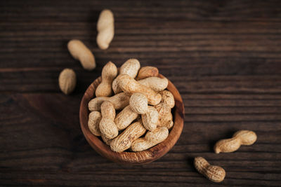 Pile of peanuts in a bowl on a dark wooden background