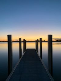 Pier over sea against clear sky during sunset