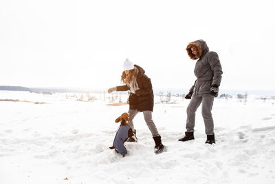 Full length of couple on snow covered field against clear sky