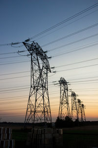 Low angle view of silhouette electricity pylon against sky during sunset