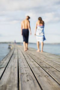 Couple wrapped in towels walking on wooden pier