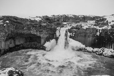 Scenic view of waterfall against sky during winter