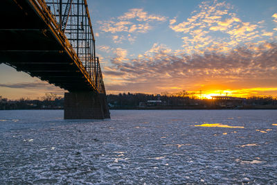 Bridge over river against sky during sunset