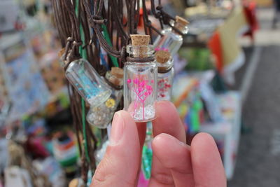 Cropped image of person holding glass bottle pendant at market stall