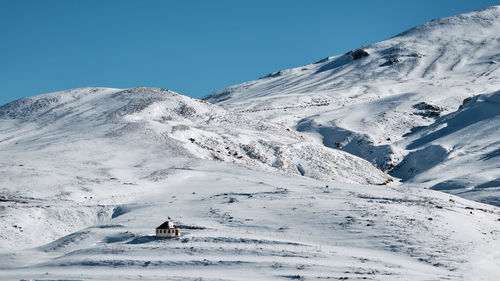 Person on snowcapped mountain against clear sky