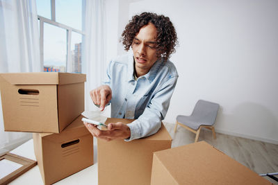 Man using smart phone by cardboard box