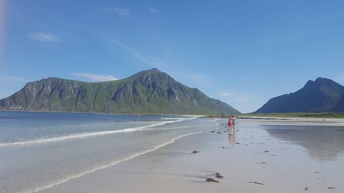 Scenic view of beach by mountains against sky