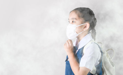 Side view portrait of a girl standing against white background