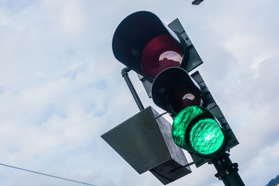 Low angle view of stoplight against cloudy sky