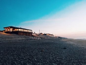 Abandoned built structure on beach against sky during sunset