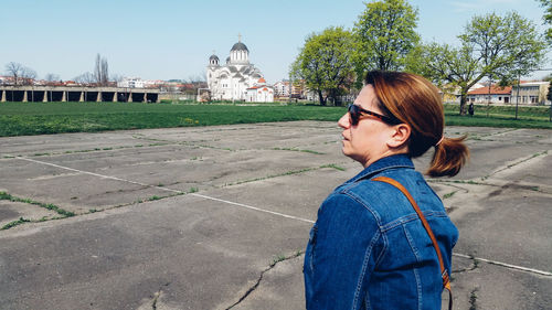 Woman in sunglasses looking away while standing by sport court