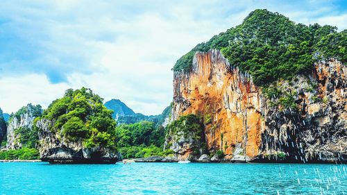 Scenic view of sea by mountain against sky