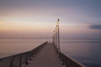 Pier over sea against sky during sunset