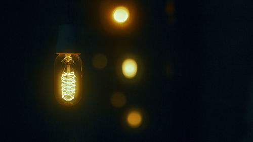 Low angle view of illuminated light bulb against black background