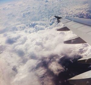 Cropped image of airplane flying over clouds