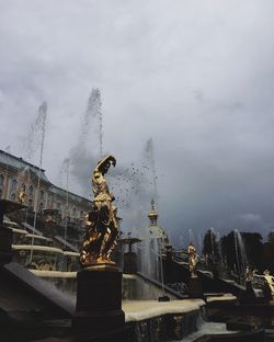 Statue by buildings against sky