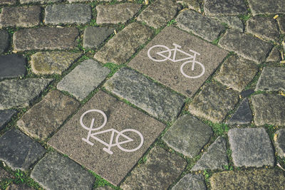 High angle view of bicycle lane signs on cobbled footpath