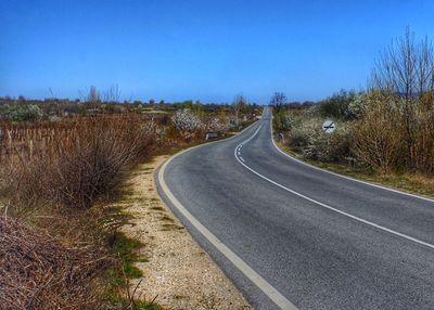 Road passing through landscape against clear sky