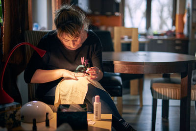 Woman painting fingernails while sitting at home