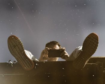 High angle view of man holding phone reflecting on water against sky