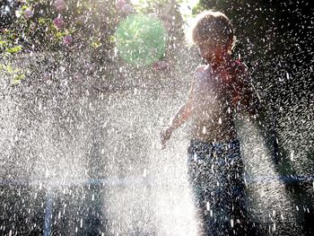 Boy enjoying water sprinkler in yard