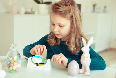 Girl looking away while sitting on table at home