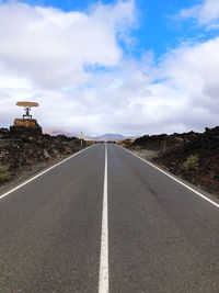 Surface level of empty road against cloudy sky