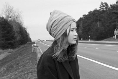 Portrait of teenage girl looking away against road