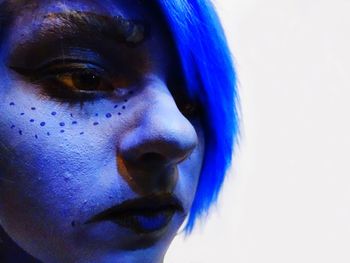 Close-up portrait of young woman against blue background