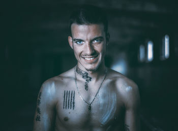 Close-up portrait of shirtless man smiling in darkroom