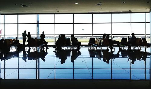 Silhouette people at airport against sky