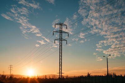 Low angle view of silhouette electricity pylon against sky during sunset