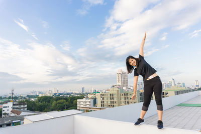 Full length of woman standing by cityscape against sky