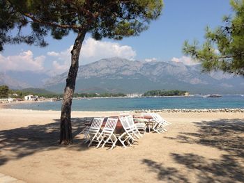 Deck chairs on beach against sky