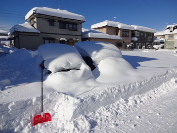 Snow covered road by building against sky