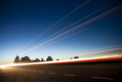 Light trails on road against sky at night