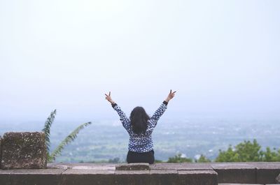 Woman raising hands against landscape