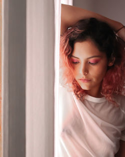 Portrait of beautiful young woman looking through window