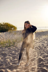 Portrait of a girl with long hair run on a sandy beach in a black leather jacket