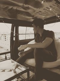 Young man looking through window while sitting on seat in boat