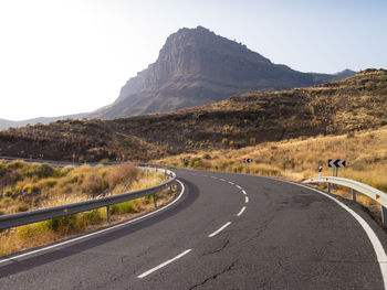 Road passing through mountain against sky